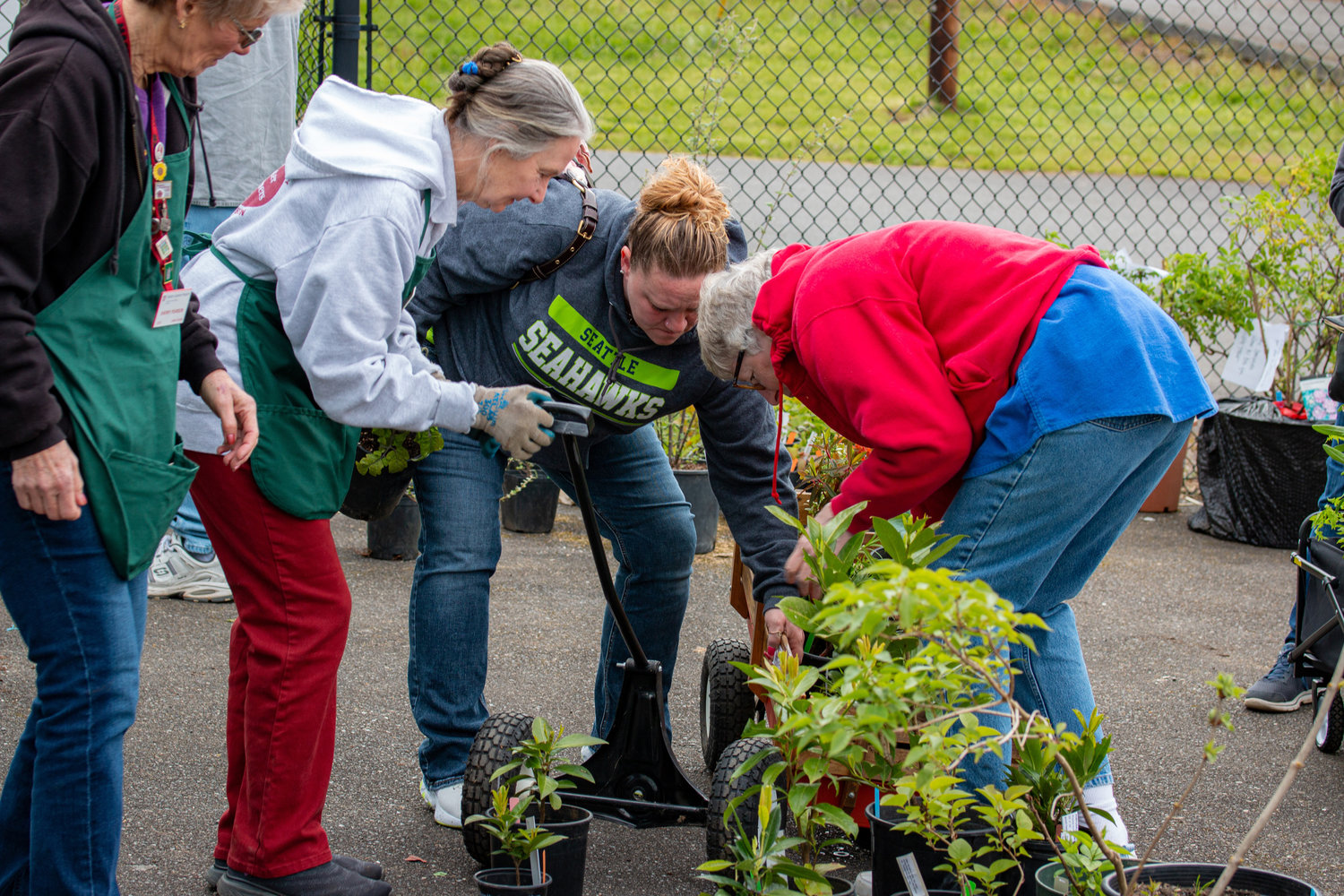 A woman is helped by others after the front wheel of her wagon became unattached at the Master Gardener Plant Sale at the Southwest Washington Fairgrounds Saturday morning.